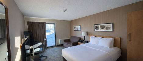Habitación de hotel con cama, escritorio, silla y vistas al exterior.