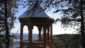A wooden gazebo with a snow-covered roof, surrounded by trees and overlooking a body of water. - Comfort Inn Baie-Comeau (Baie Comeau)