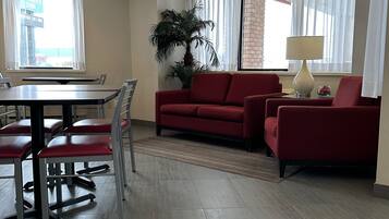 A modern living room with a red sofa, a dining table with chairs, and a large window with curtains.