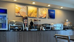 A modern breakfast bar with a coffee machine, a microwave, and a food display. - Comfort Inn Baie-Comeau (Baie Comeau)