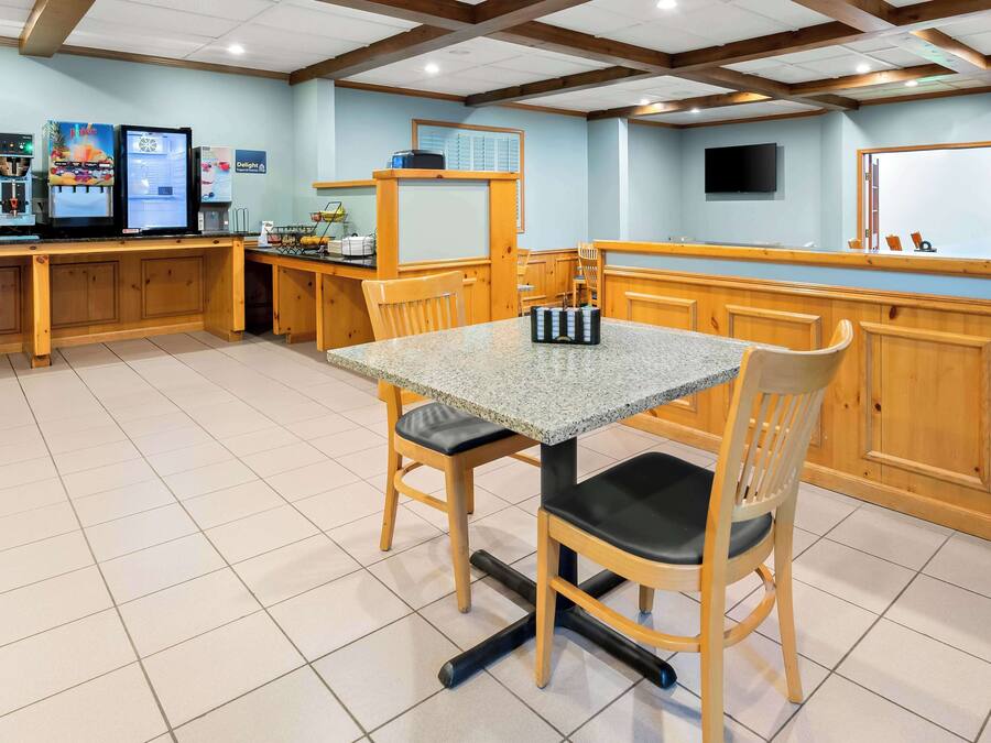 Un restaurante con mostrador de madera, una mesa con sillas y una pizarra con el menú.