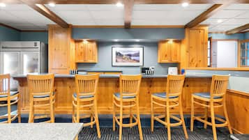 A kitchen with wooden cabinets, a refrigerator, and bar stools.