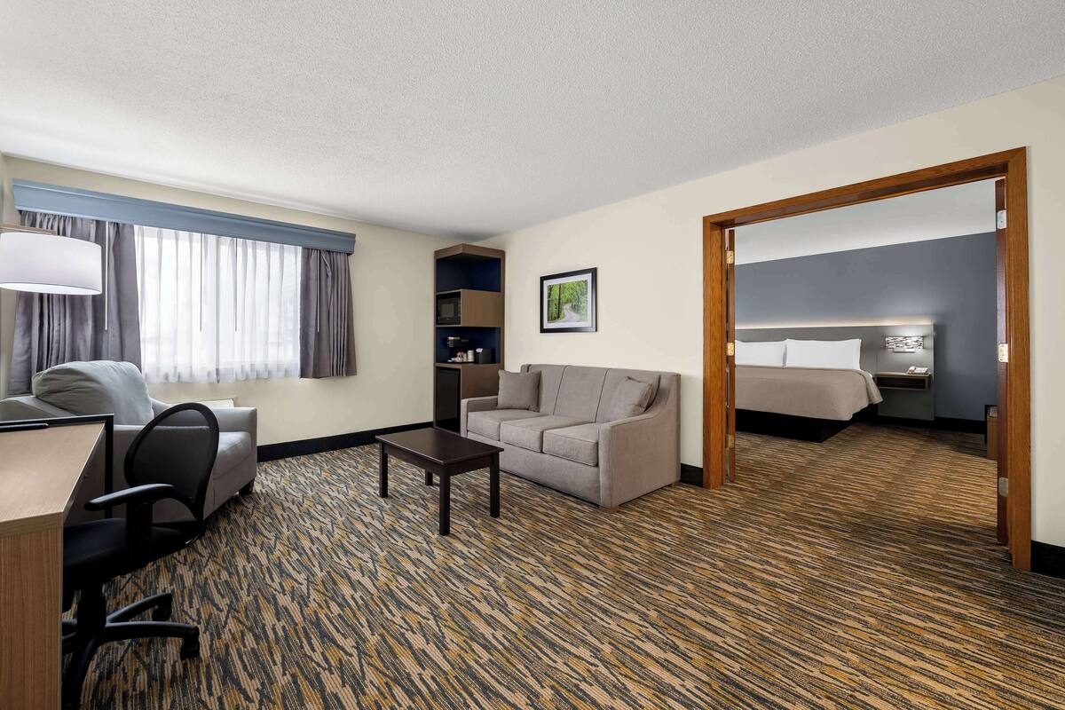 A hotel room with a desk, office chair, sofa, and a bed.
