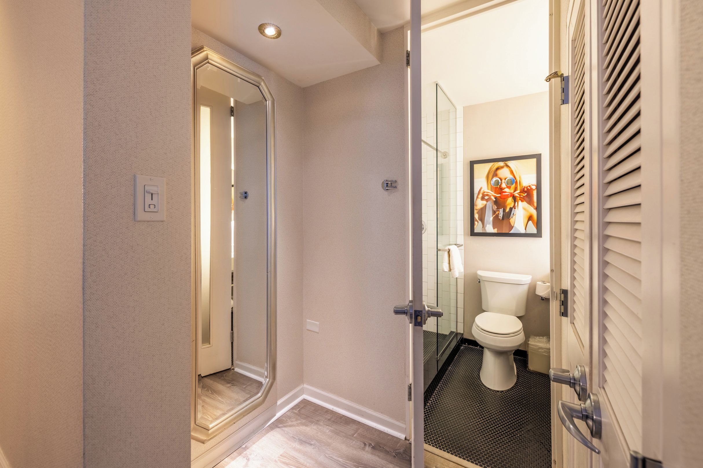 A modern bathroom with a glass shower enclosure, a toilet, and a framed picture on the wall.