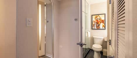 A modern bathroom with a glass shower enclosure, a toilet, and a framed picture on the wall.