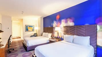 A hotel room with two beds, a desk, a chair, and a wall with a colorful abstract painting.