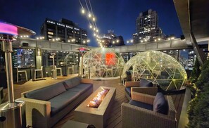 An outdoor rooftop lounge with seating, a fire feature, and a view of the city skyline at night. - The Chicago Hotel Collection - Magnificent Mile (Chicago)