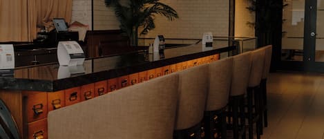 A bar area with a long counter, multiple stools, and pendant lighting.