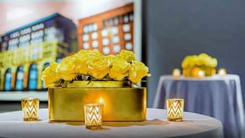 A table with a gold vase containing yellow roses, flanked by two small, patterned candle holders.