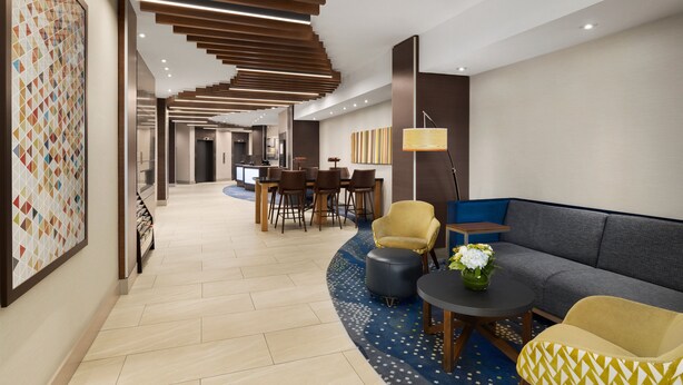 A modern lobby with a dining area, sofas, and a patterned wall. - Holiday Inn Express Vancouver-Metrotown (Burnaby) by IHG (Burnaby)