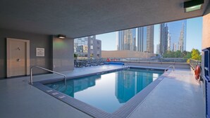 A rooftop pool with a view of tall buildings, a lifeguard chair, and a warning sign. - Holiday Inn Express Vancouver-Metrotown (Burnaby) by IHG (Burnaby)