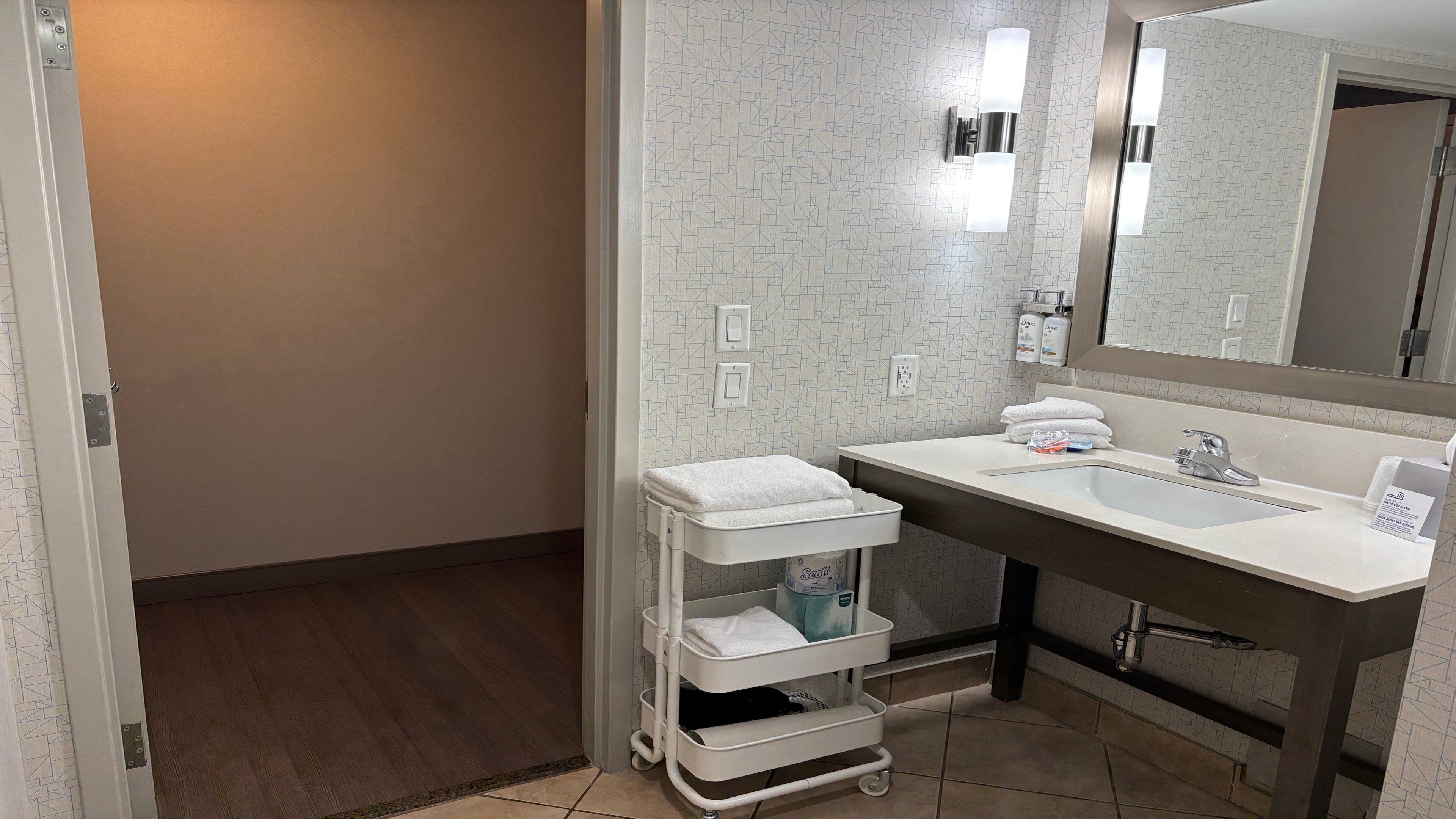 A modern bathroom with a white sink, a mirror, and a white towel rack.