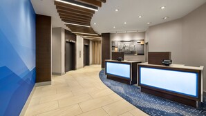 A modern hotel lobby with a reception desk, a kitchen area, and a curved hallway. - Holiday Inn Express Vancouver-Metrotown (Burnaby) by IHG (Burnaby)