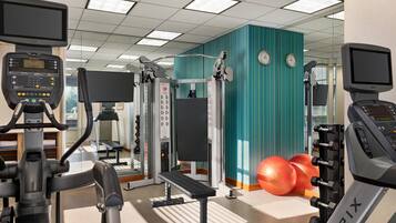 Une salle de sport équipée de divers appareils d’exercice, notamment des tapis de course, un banc et des appareils de musculation.