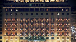 Un grand hôtel à plusieurs étages, doté d’une façade symétrique avec des fenêtres et des balcons uniformément éclairés.