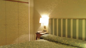 Een kamer met een bed, nachtkastje, lamp en kledingkast.