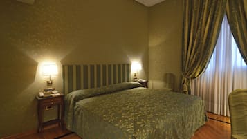 Una habitación de hotel con una cama grande, dos lámparas de noche, una mesita de noche y una silla.