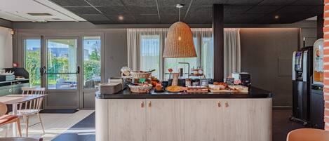 A modern kitchen with a central island, a hanging light fixture, and a view of the outdoors.