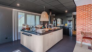 Una cocina moderna con una isla central, una cafetera y un expositor de pan.