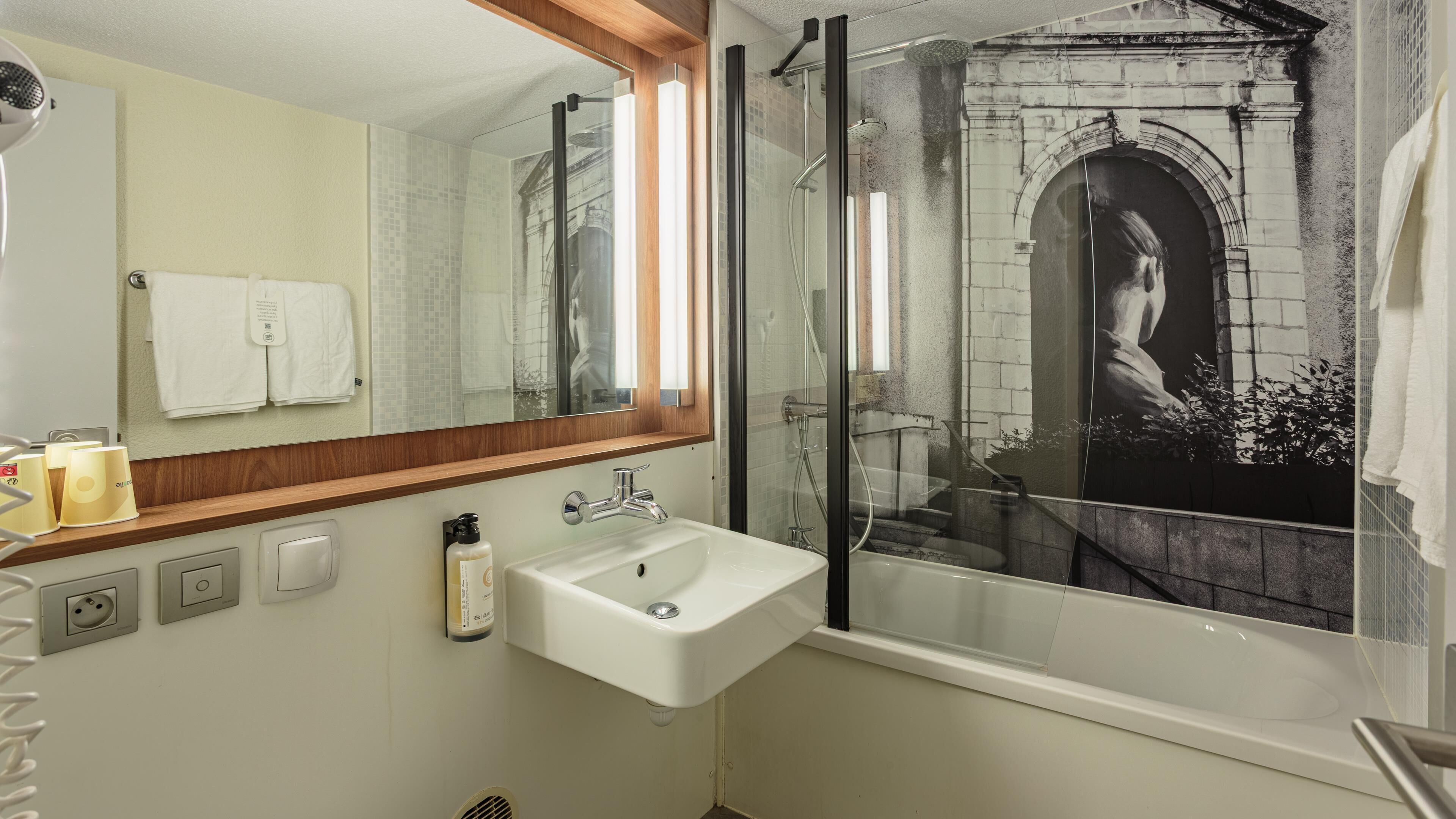A bathroom with a large mirror, a sink, a shower, and a bathtub.