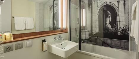 A bathroom with a large mirror, a sink, a shower, and a bathtub.