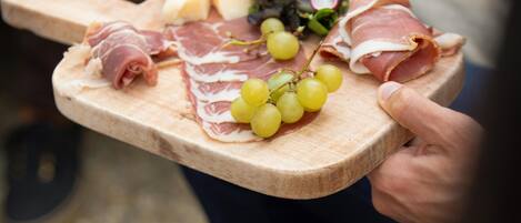 A wooden board with various cheeses, cured meats, and grapes.