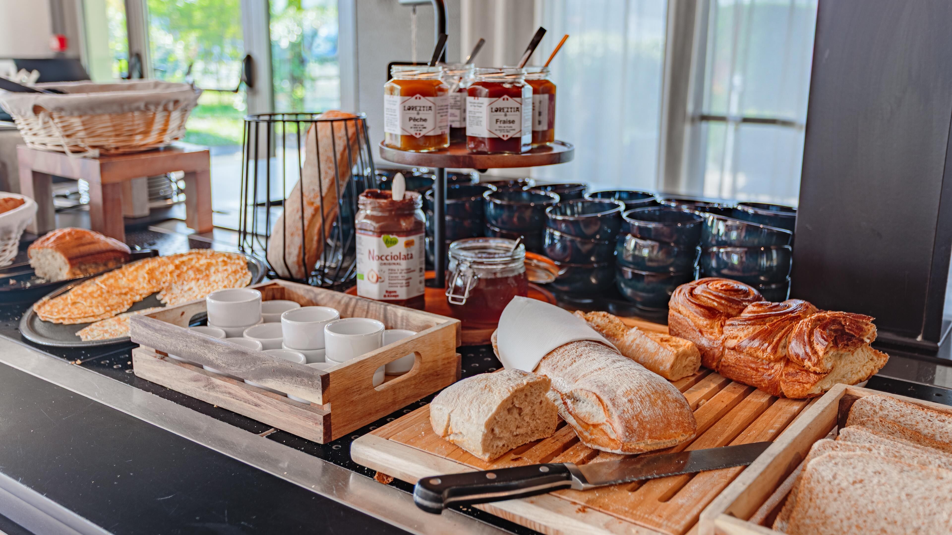 Un bufé de desayuno con pan, bollería y salsas.