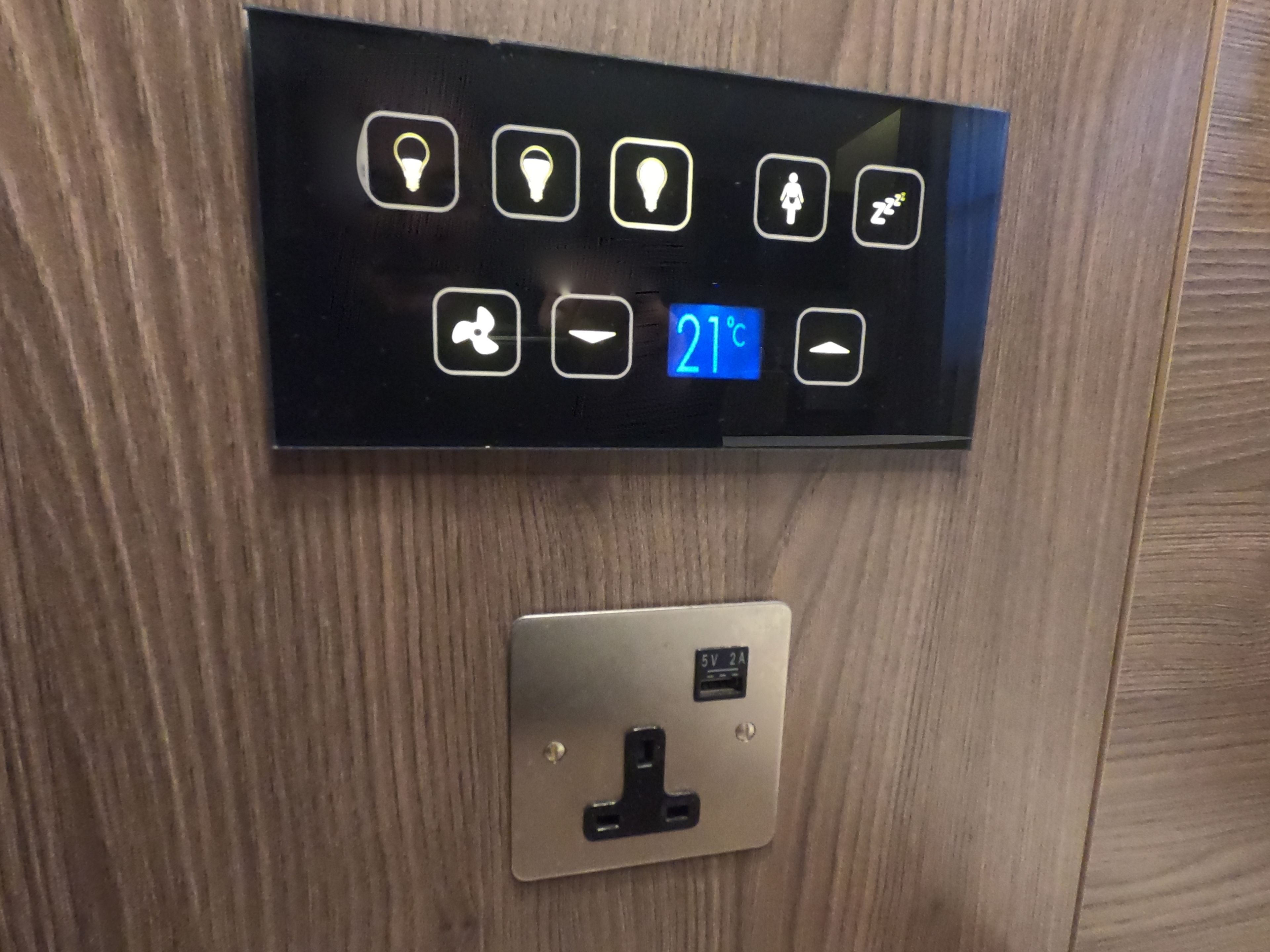 A control panel with illuminated icons and a digital display showing 21°C.