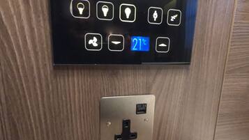 Panel de control con iconos iluminados y una pantalla digital que muestra 21 grados Celsius.