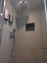 Eine Dusche mit Handbrause, einer fest installierten Bedienung und einem kleinen Fenster.