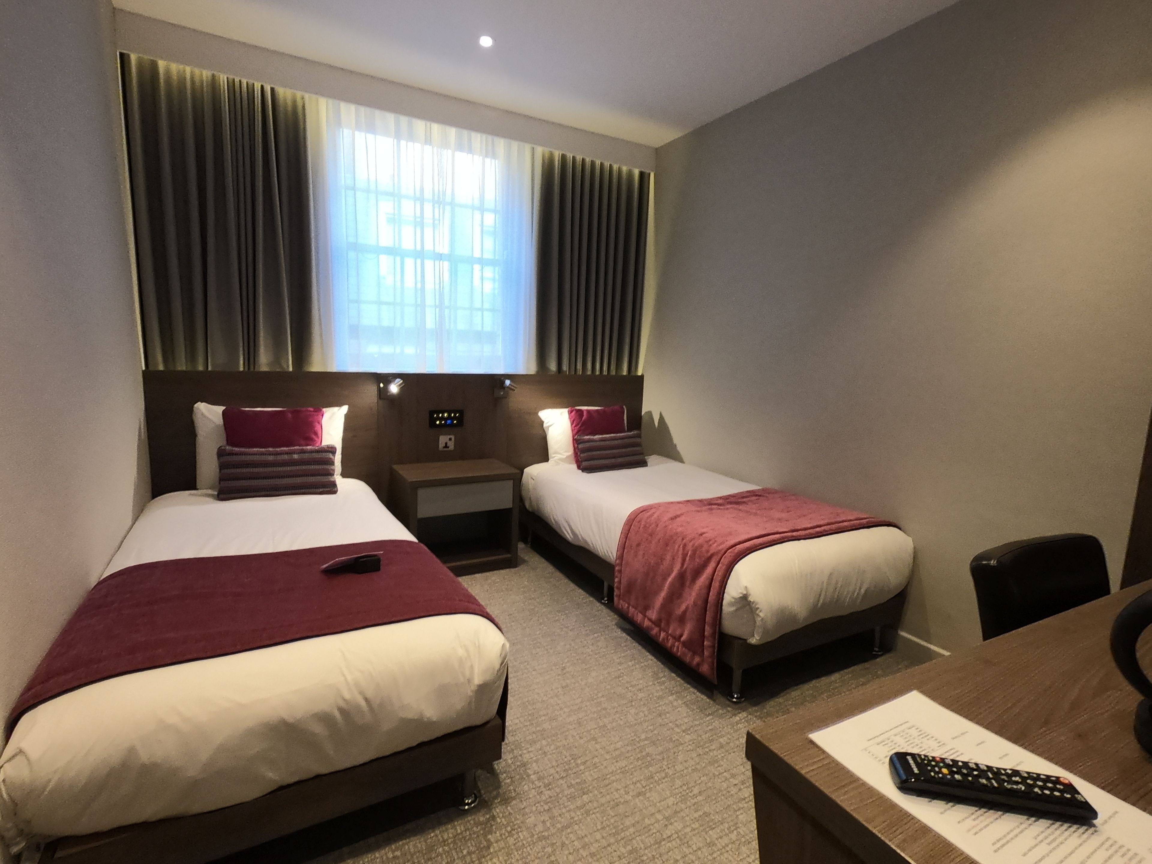 Habitación de hotel con dos camas, un escritorio y una silla.