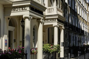 Hotellin julkisivussa on pylväitä, ja siinä on kyltti, jossa lukee ”HOTEL DELMERE”, sekä kukkaistutuksia.