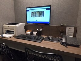 Ein Hotelrezeptionstresen mit Computermonitor, Drucker, Tastatur, Maus und Telefon.