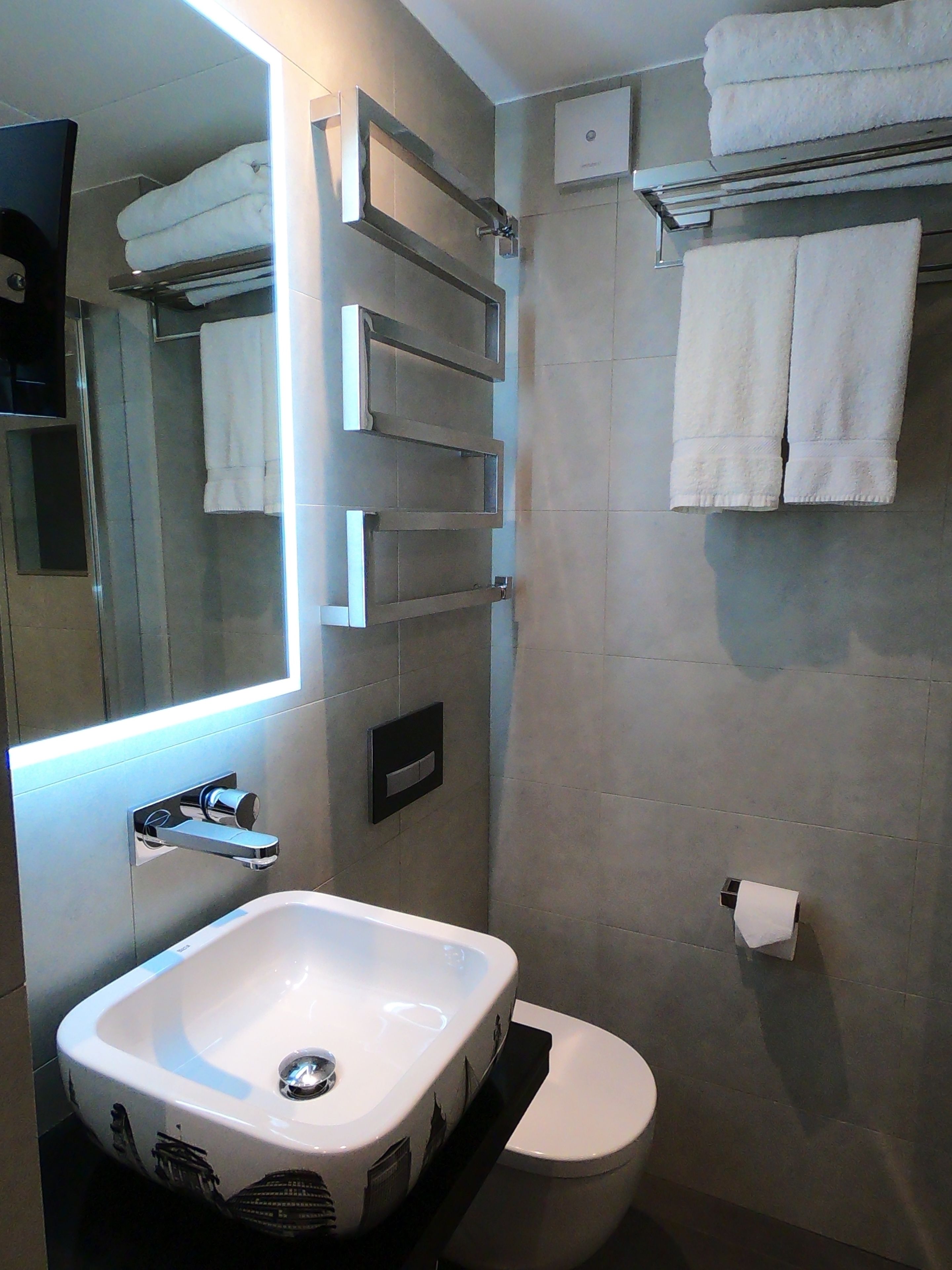 Un baño moderno con un lavamanos, inodoro y espejo blancos.