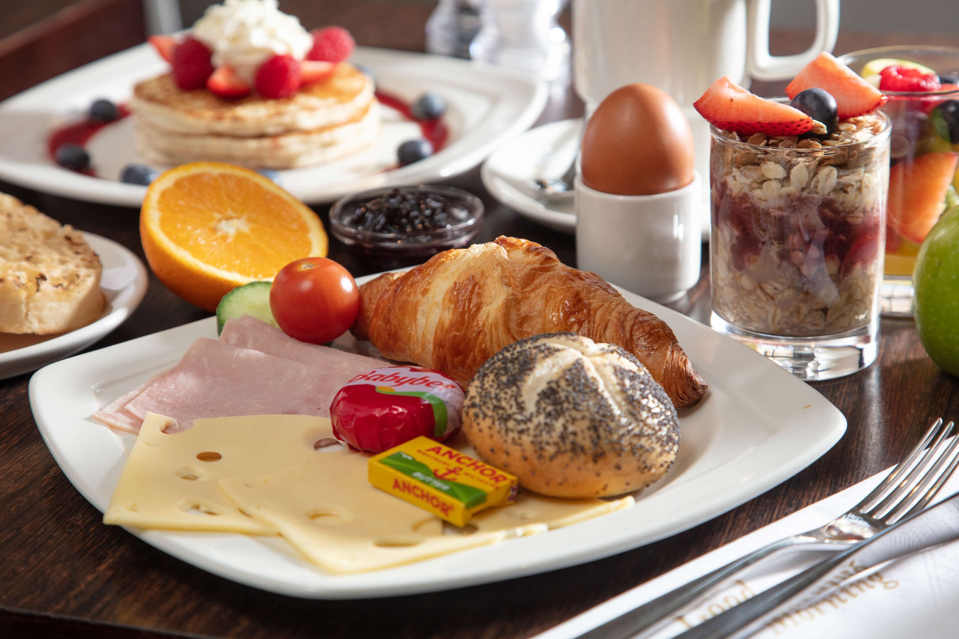 Une assiette de petit-déjeuner comprenant des croissants, du fromage, du jambon et un croissant aux graines de pavot.