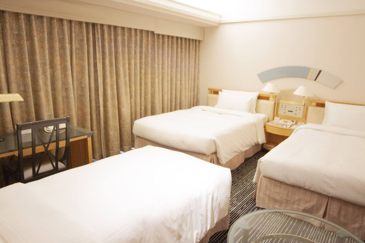 Een hotelkamer met twee bedden, een bureau en een stoel.