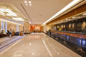 A hotel lobby with a reception desk, seating area, and a polished floor. - Hotel New Otani Makuhari (Chiba)