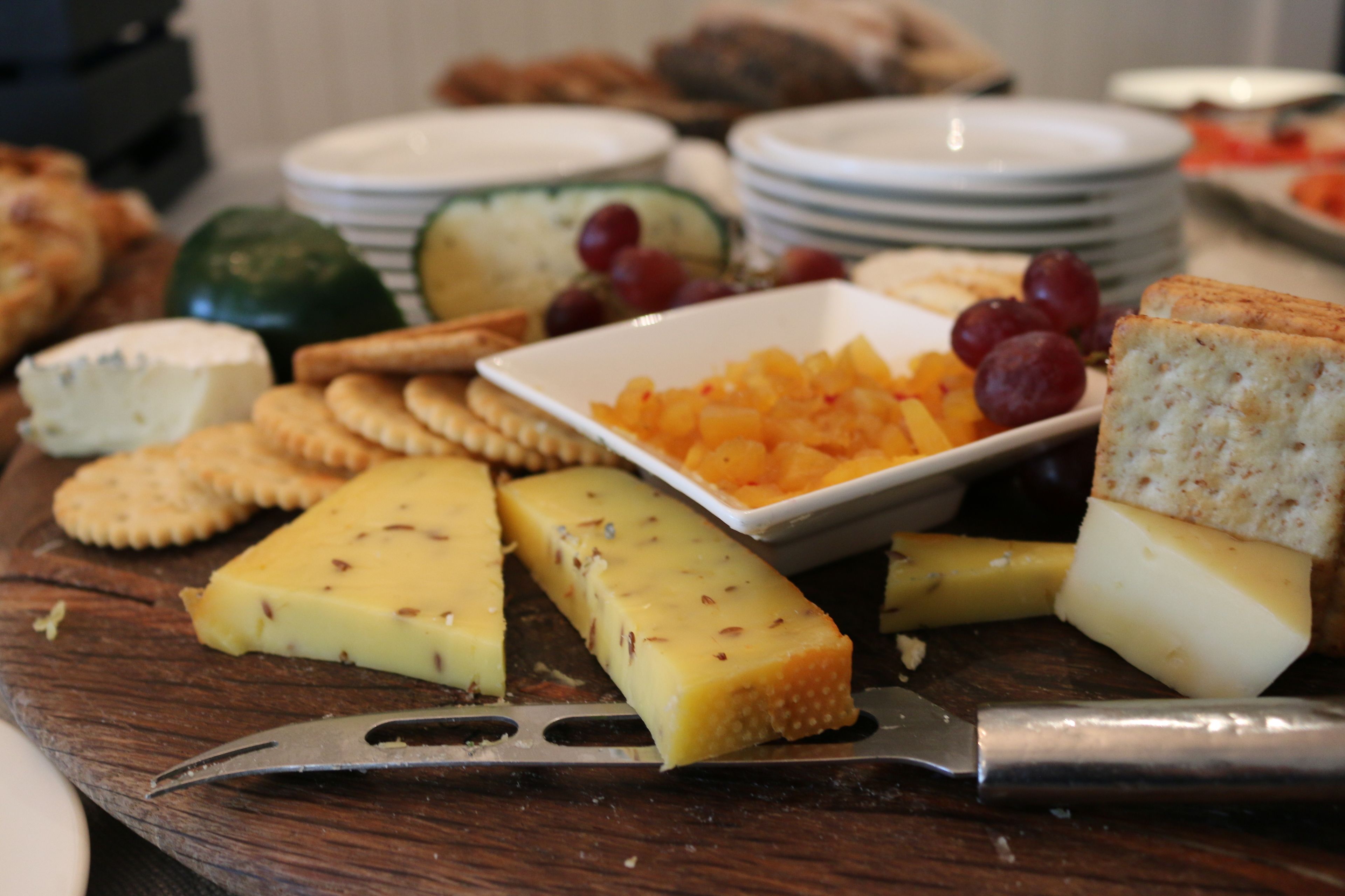 A variety of cheeses and crackers on a wooden board.