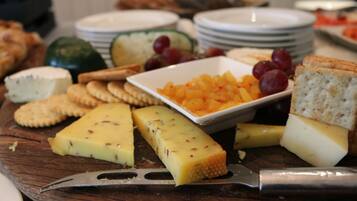 A variety of cheeses and crackers on a wooden board.