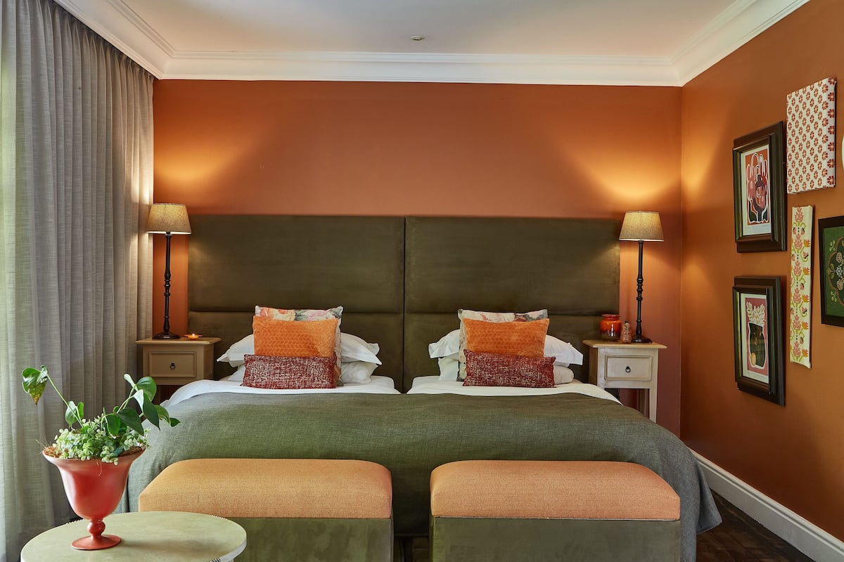 A double bed with two nightstands, a potted plant, and a small round table.