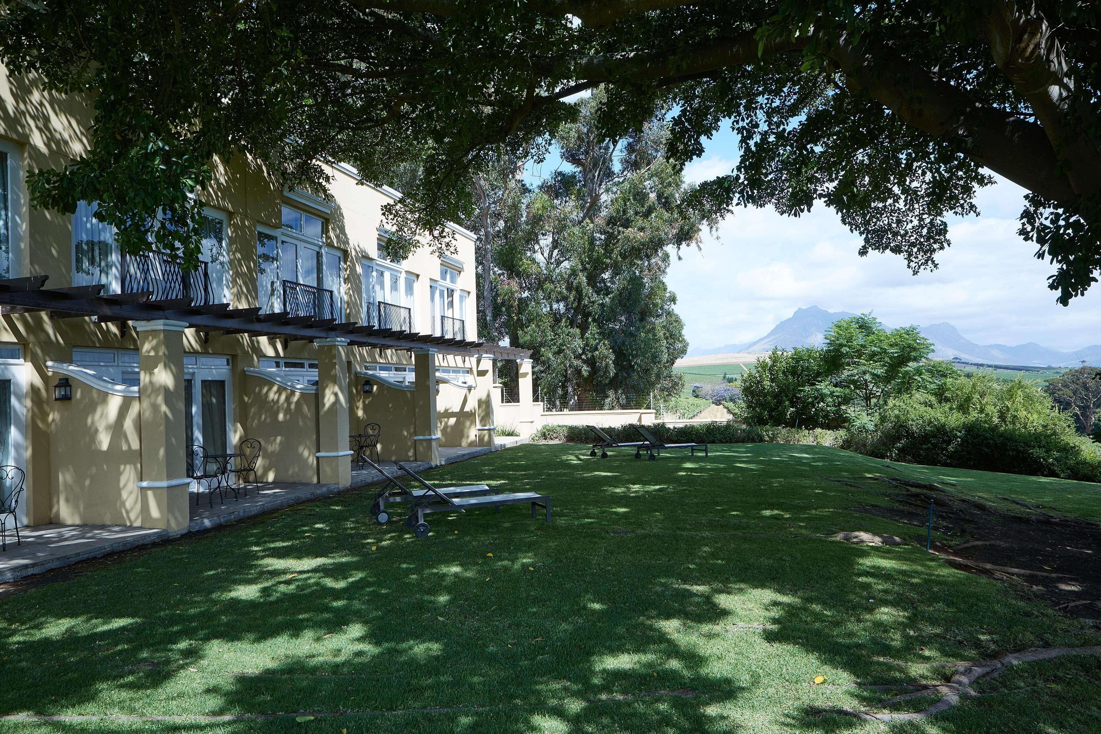 Ein Hotel mit überdachter Außenbereich, einem gepflegten Rasen und Blick auf ferne Berge.