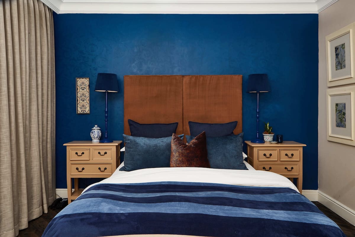 A bedroom with a large bed, two bedside tables, and a headboard.