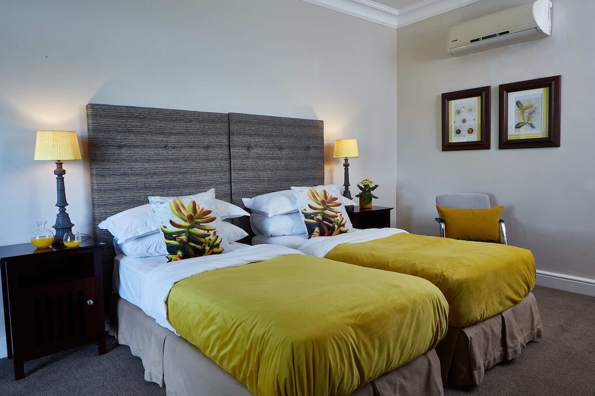 A double bed with a dark headboard, two bedside tables with lamps, and a chair with a yellow cushion.
