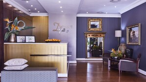 A modern hotel lobby with a reception desk, a bench, and a dining area. - The Devon Valley Hotel (Stellenbosch)