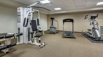 Un gimnasio con diversos equipos de ejercicio, incluyendo una máquina de pesas, una cinta de correr y una elíptica.