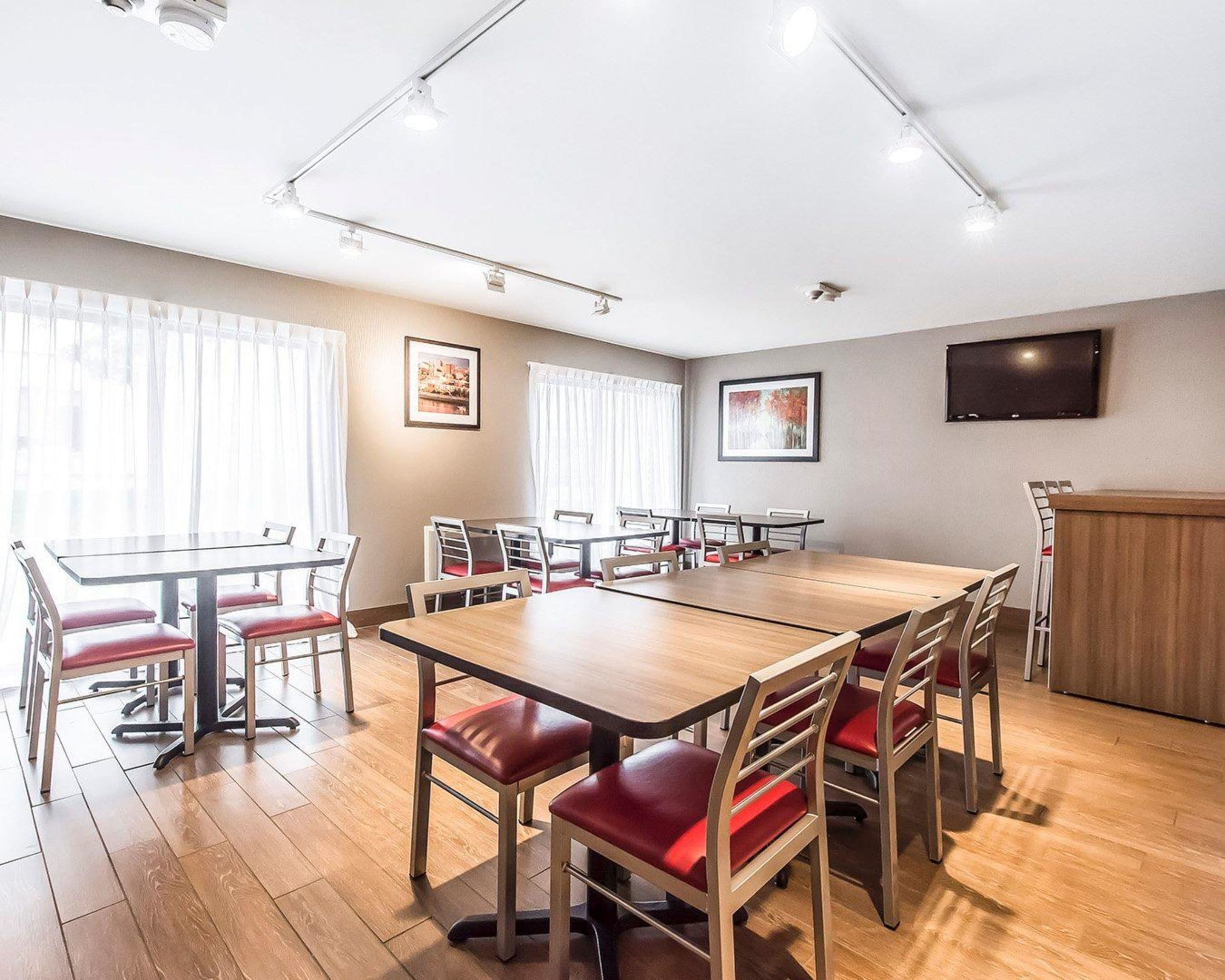 A conference room with a long table, multiple chairs, and a television on the wall.