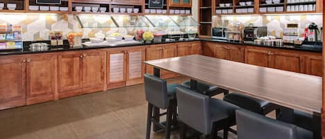 A spacious kitchen with wooden cabinets, a long counter, and a seating area with chairs.