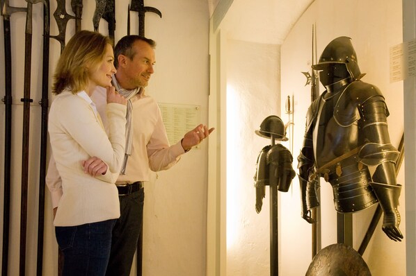 A couple observing a medieval knight armor exhibit. - Hotel Merian Rothenburg (Rothenburg ob der Tauber)