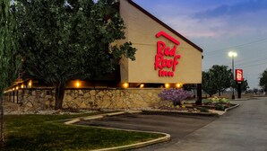 A Red Roof Inn with a stone facade, a large tree, and a well-lit entrance. - Red Roof Inn Lansing East – MSU (Lansing)