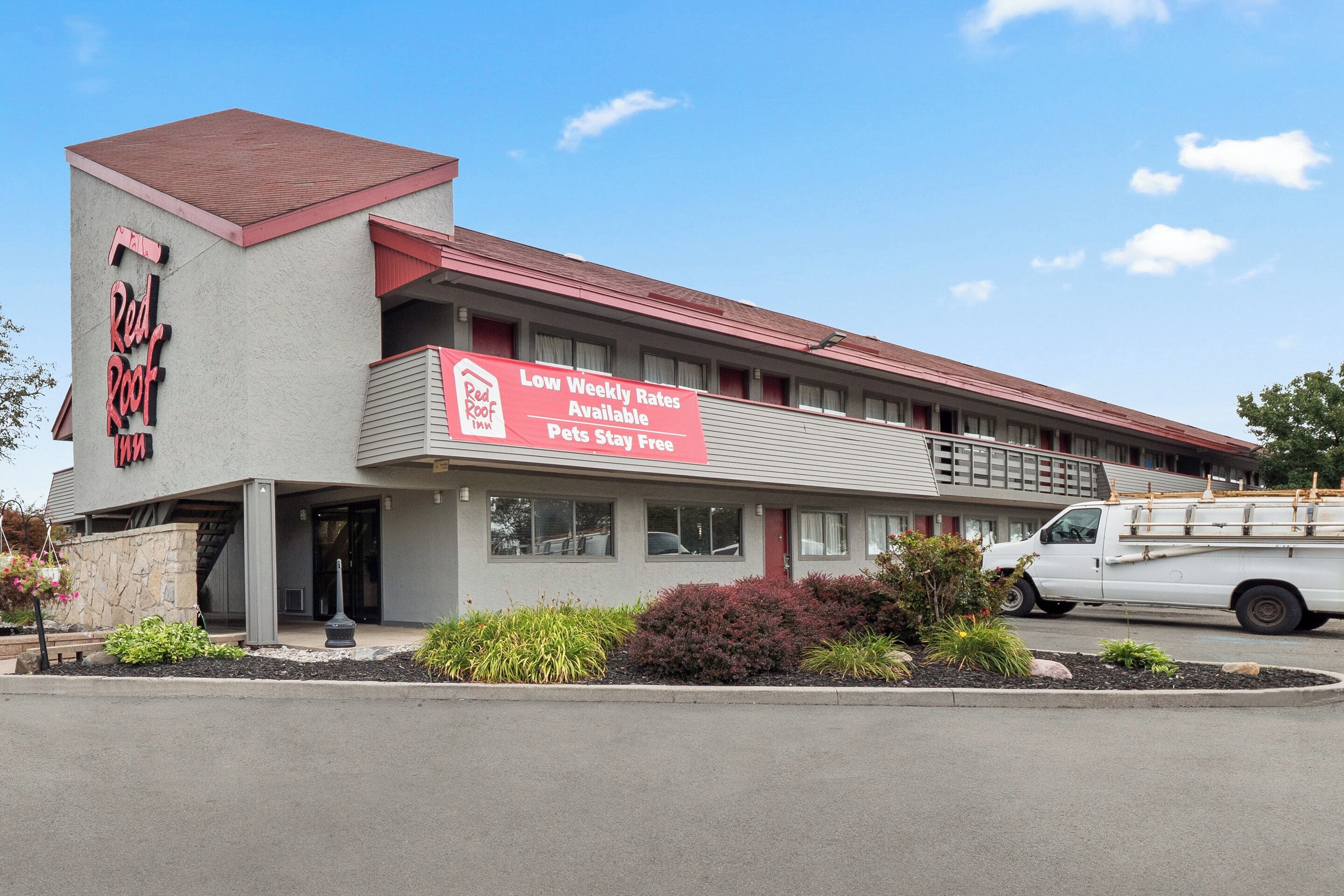 A Red Roof Inn with a sign advertising low weekly rates and free pet stay.
